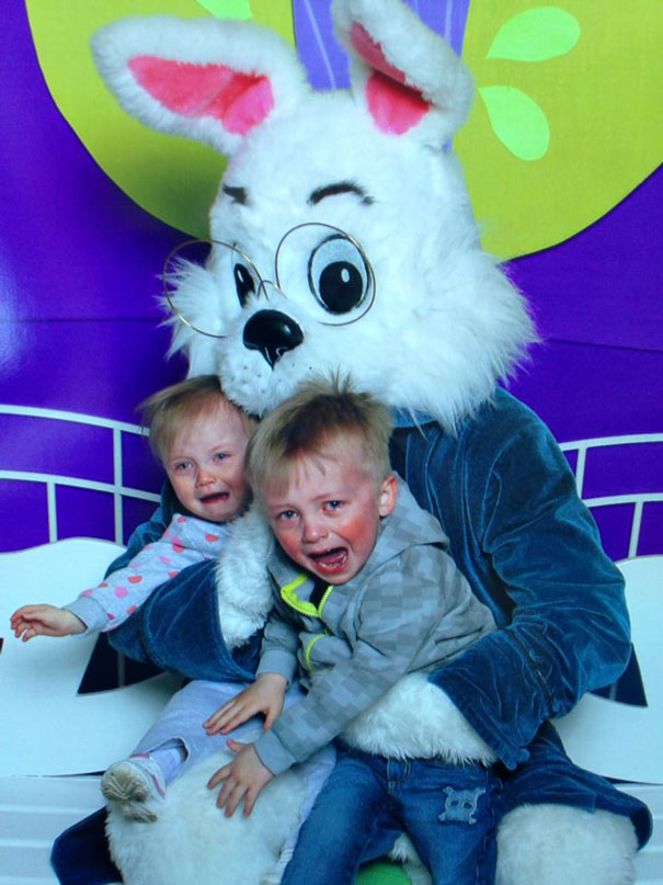 Two children crying while sitting on the lap of a vintage Easter Bunny with oversized glasses.