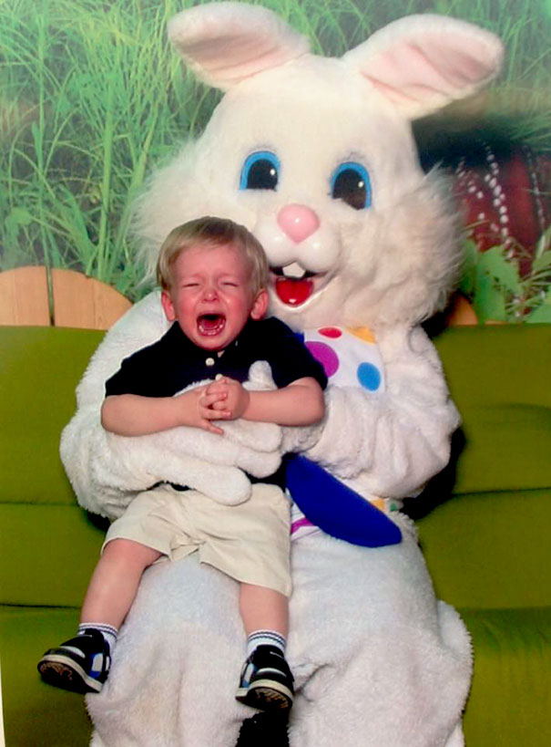 A child crying on the lap of a large vintage Easter bunny wearing a polka dot bow tie.