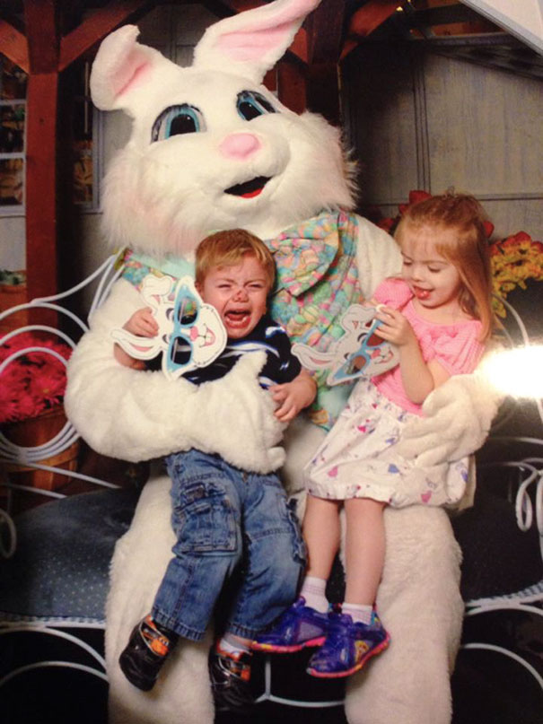Two children on a vintage Easter bunny's lap; one is crying, the other looks uneasy.