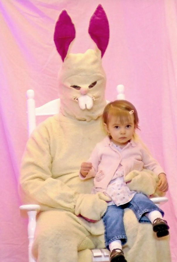 Vintage Easter Bunny costume with a child on its lap, set against a pink background.