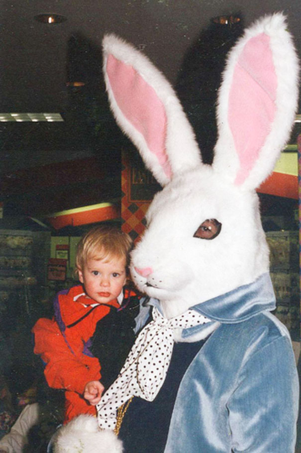 A child in a red coat being held by a vintage Easter bunny in a blue jacket and polka dot scarf.