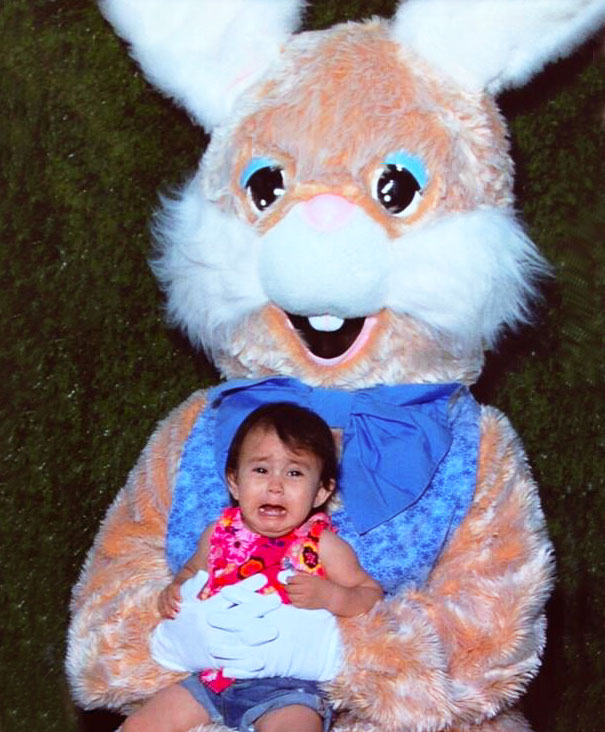 Scared child sitting on the lap of a vintage Easter bunny with a big smile and fluffy costume.