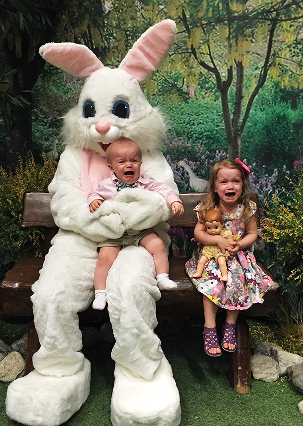 Crying children sitting with a giant vintage Easter bunny in a garden setting.