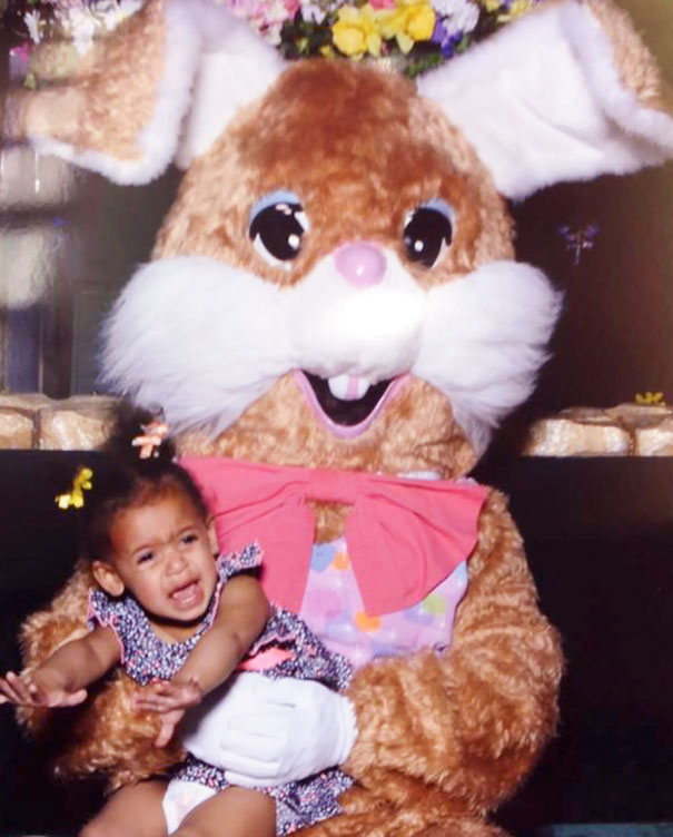 Child looking scared while sitting with a vintage Easter Bunny costume.