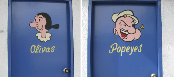 Funny bathroom signs featuring cartoon characters on blue doors labeled Olivas and Popeyes.