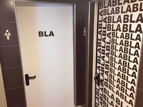Funny bathroom sign with "BLA" repeated pattern on doors, bringing humor to restroom design.