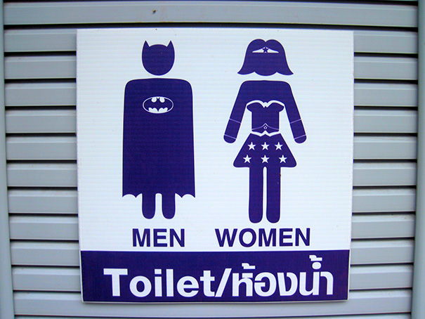 Funny bathroom signs featuring superhero-themed symbols for men and women.