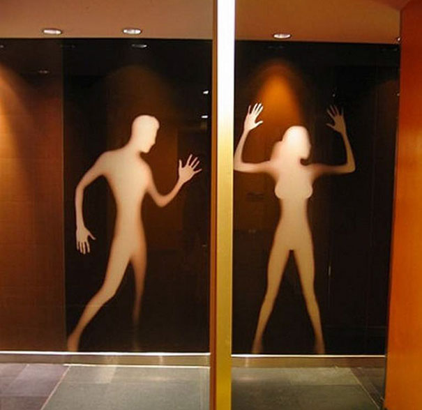 Funny bathroom signs with silhouettes of a man and woman on frosted glass doors.