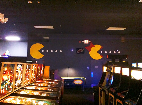 Arcade-inspired bathroom sign with Pac-Man characters chasing dots, adding humor to the space.