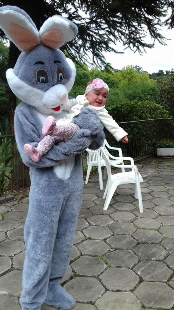 Vintage Easter Bunny holding a crying baby on a patio with chairs.