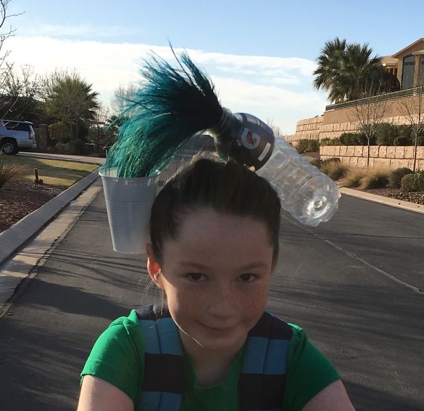 Child with creative crazy hair day style featuring a water bottle and cup, walking outside on a sunny day.