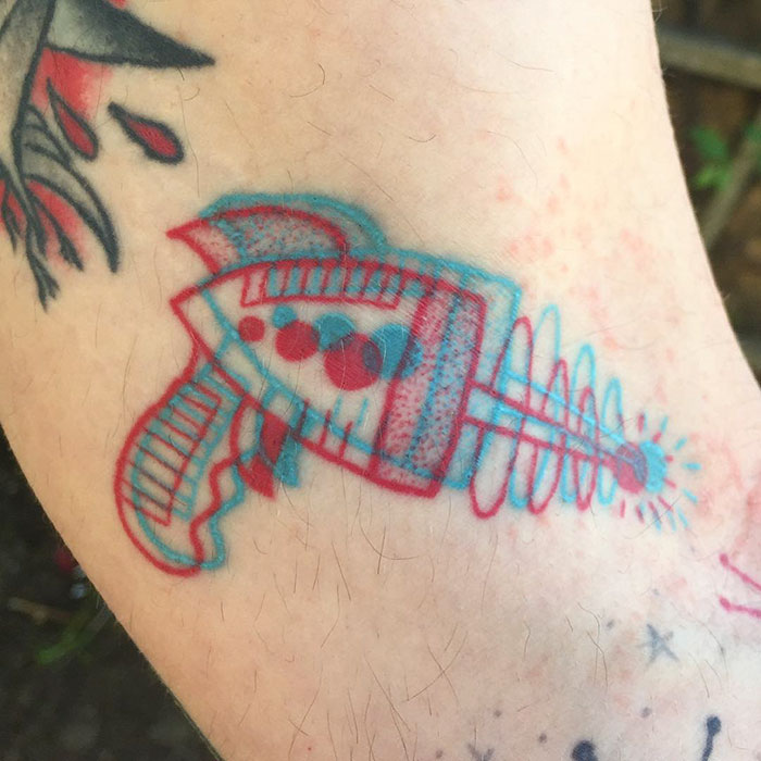 3D-inspired tattoo of a retro ray gun with red and blue colors, creating a vibrant and futuristic effect on skin.