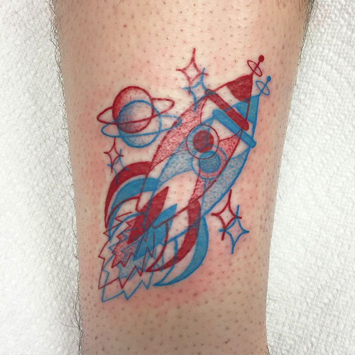 3D-inspired tattoo of a colorful space rocket with planets and stars on skin.