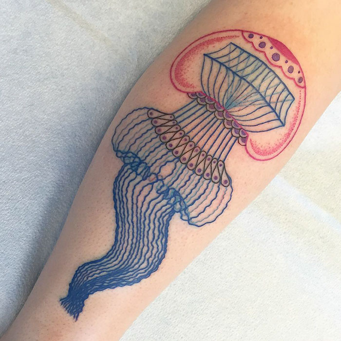 3D-inspired jellyfish tattoo with vibrant colors on a forearm.