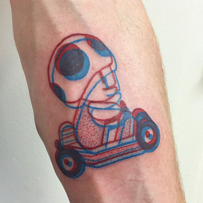 3D-inspired tattoo of a cartoon character on a person's arm in red and blue ink.