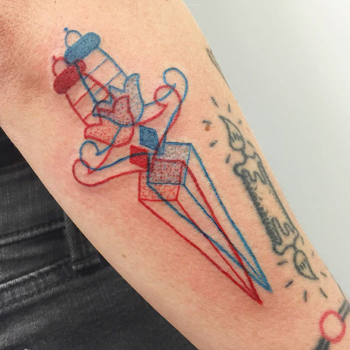 3D-inspired tattoo with geometric shapes and vibrant colors on a person's arm.