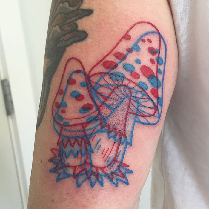 3D-inspired tattoo of colorful mushrooms with overlapping red and blue outlines on an arm.