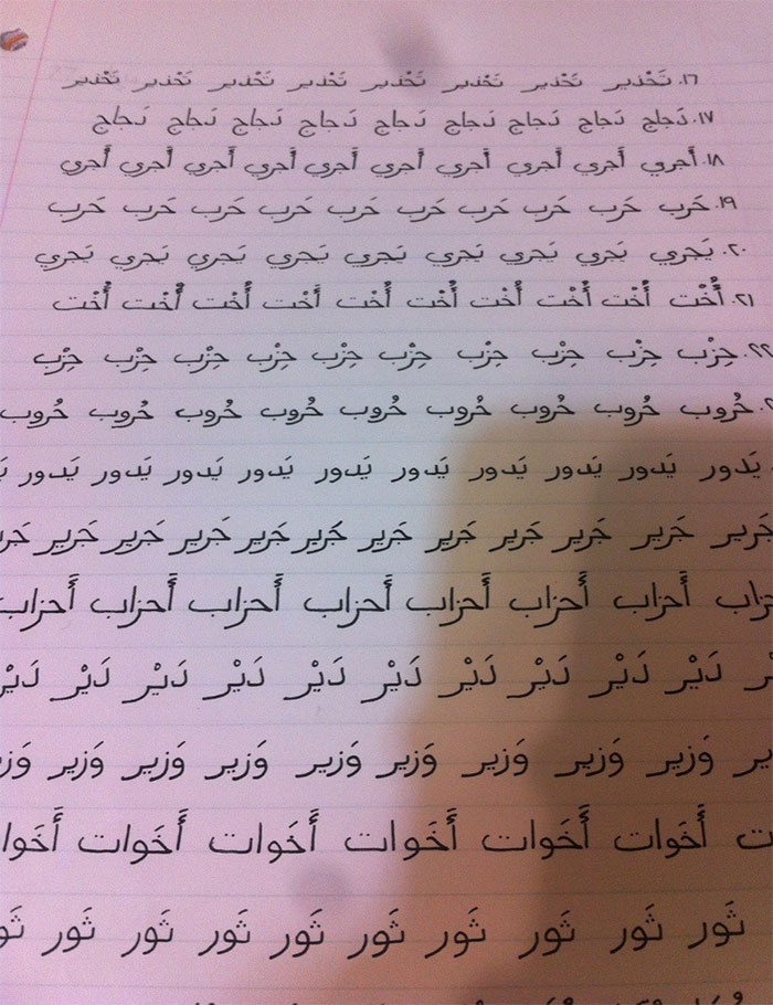 Beautiful handwriting in Arabic script on lined notebook paper, showcasing artistic penmanship.