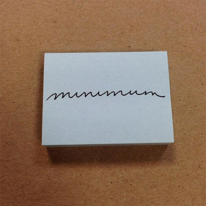 Beautiful handwriting of the word "minimum" on a white card against a brown background.
