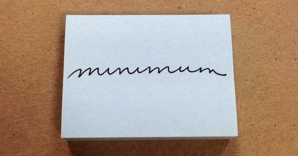 A white card with beautiful handwriting spelling out a word in elegant cursive on a wooden surface.