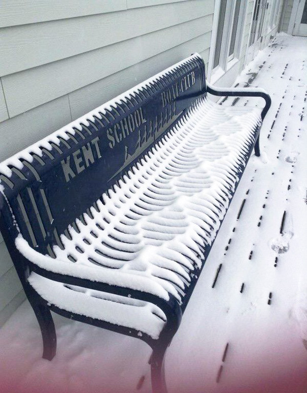 Snow-covered bench with perfectly aligned snow patterns, satisfying perfectionist's soul in a serene setting.