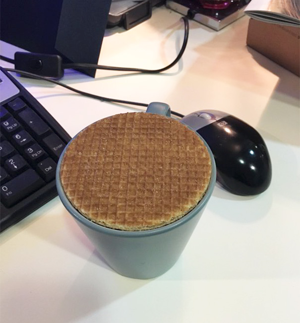 Perfectly fitting waffle on a mug beside a keyboard and mouse on a desk, pleasing for perfectionists.