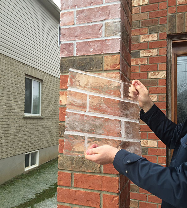 Clear ice sheet peeling off a red brick wall, satisfying a perfectionist’s soul.