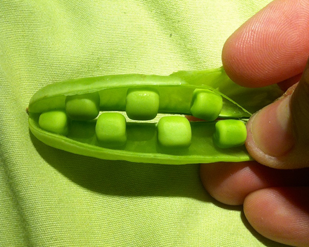A perfectly aligned row of peas inside a bright green pod, satisfying perfectionist aesthetics.