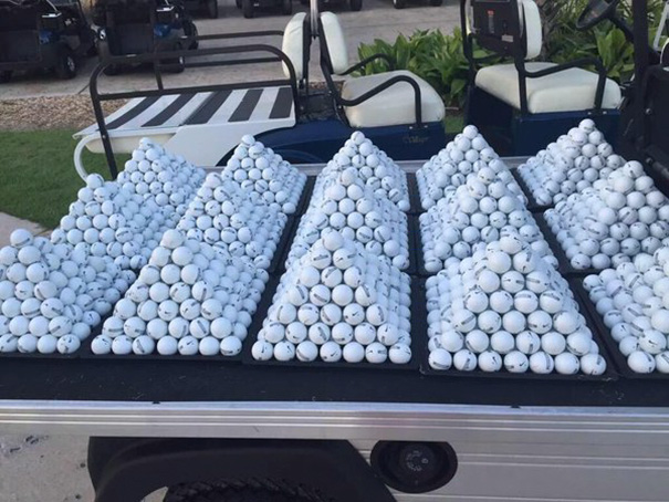 Neatly stacked pyramids of golf balls on a cart, satisfying perfectionists.