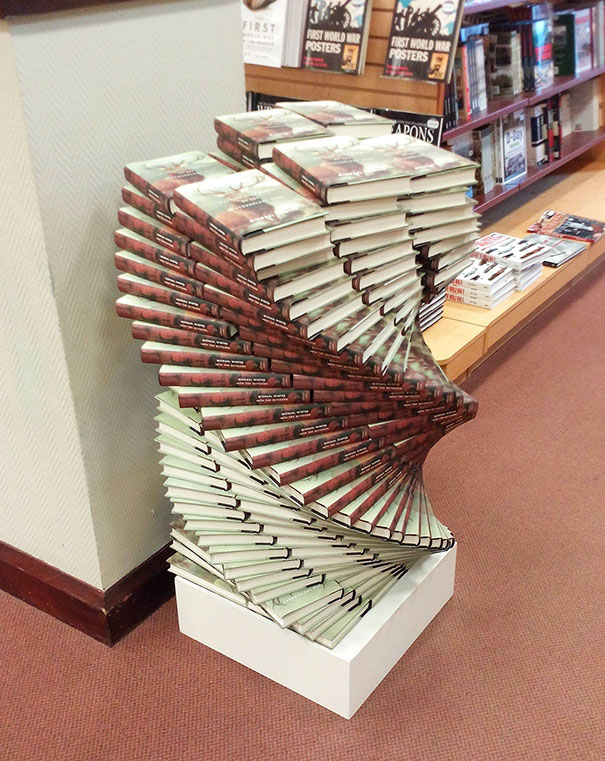Meticulously stacked books creating a perfect spiral shape in a bookstore, satisfying every perfectionist's soul.