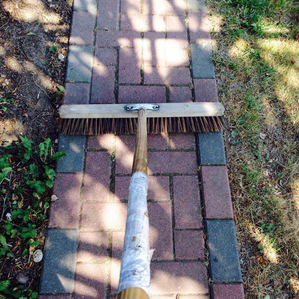 Perfect alignment of a broom on a brick pathway, satisfying a perfectionist's soul.