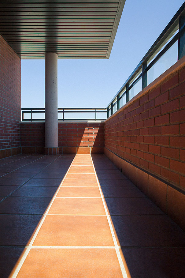 Symmetrical balcony view with perfect alignment of brick walls and tiles, bathed in sunlight, satisfying perfectionists.