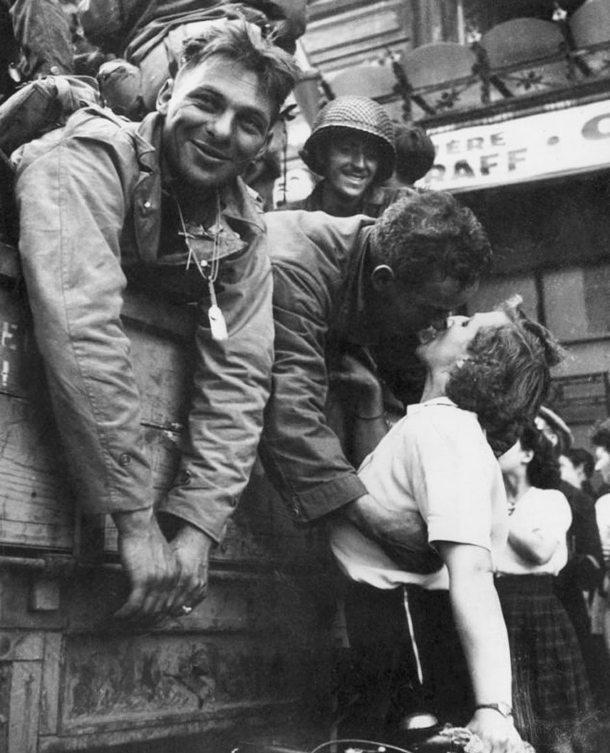 An American Soldier Leans Over The Side Of An Army Vehicle As He Kisses A French Woman On A Bicycle During The Liberation Of Paris, 1944