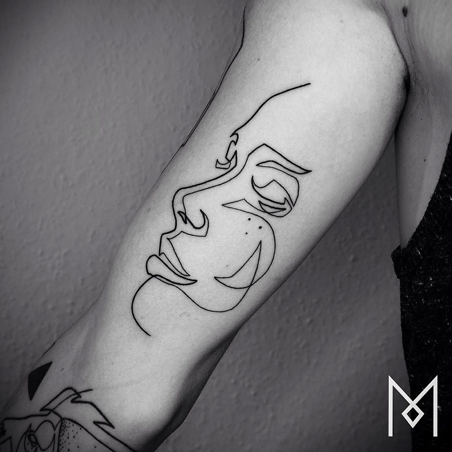 Minimalist single line tattoo of a face by Iranian-German artist on arm.