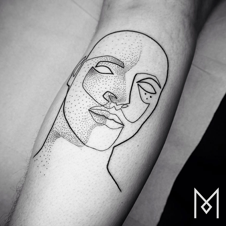 Minimalist single line tattoo of an abstract face with dotted details on skin.
