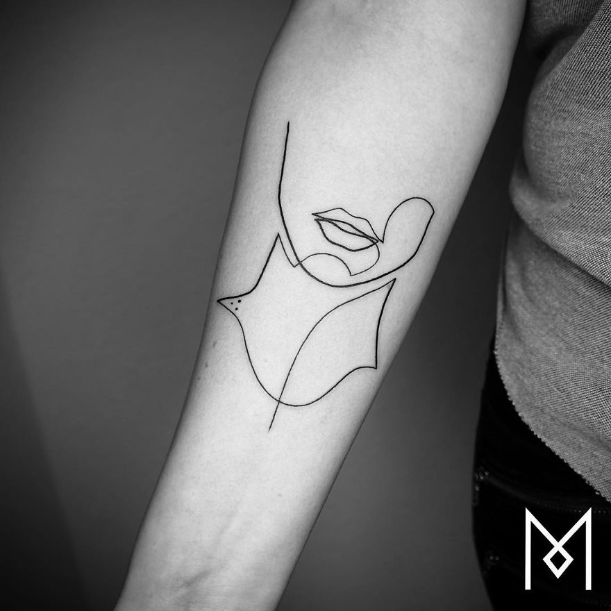 Minimalist single line tattoo of a woman's face and a leaf on an arm, created by Iranian-German artist.