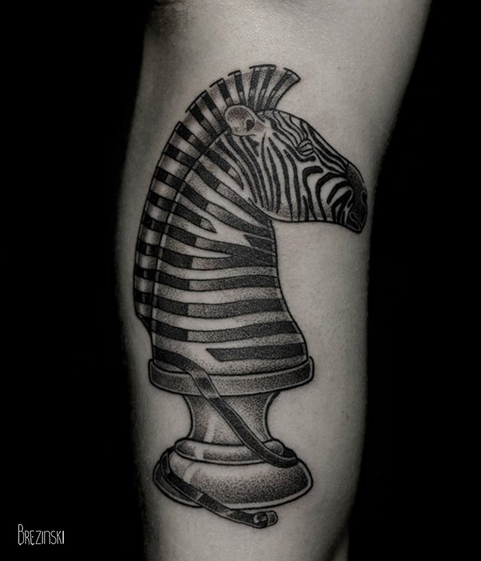 Surreal tattoo by Belarussian artist Ilya Brezinski featuring a zebra chess piece design on the forearm.