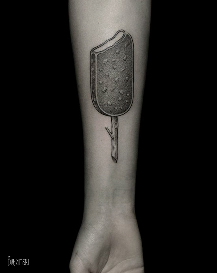 Arm with a surreal tattoo of an ice cream bar stick by a Belarussian artist.