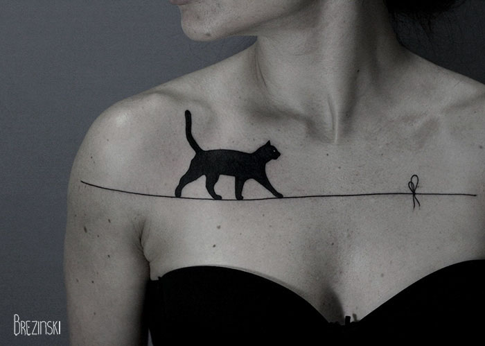 Surreal tattoo of a black cat walking on a line across a woman's chest, created by a Belarussian artist.