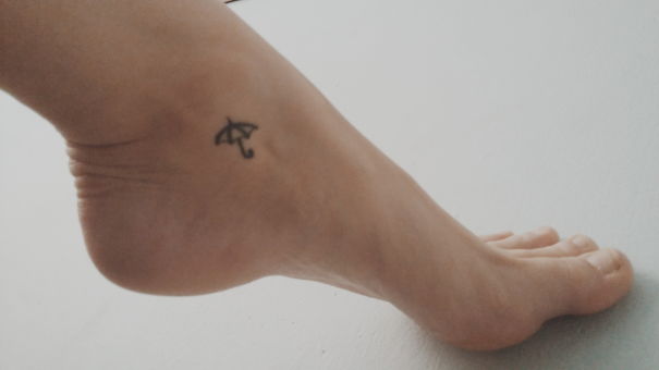 Small foot tattoo of an umbrella on the side of a foot.