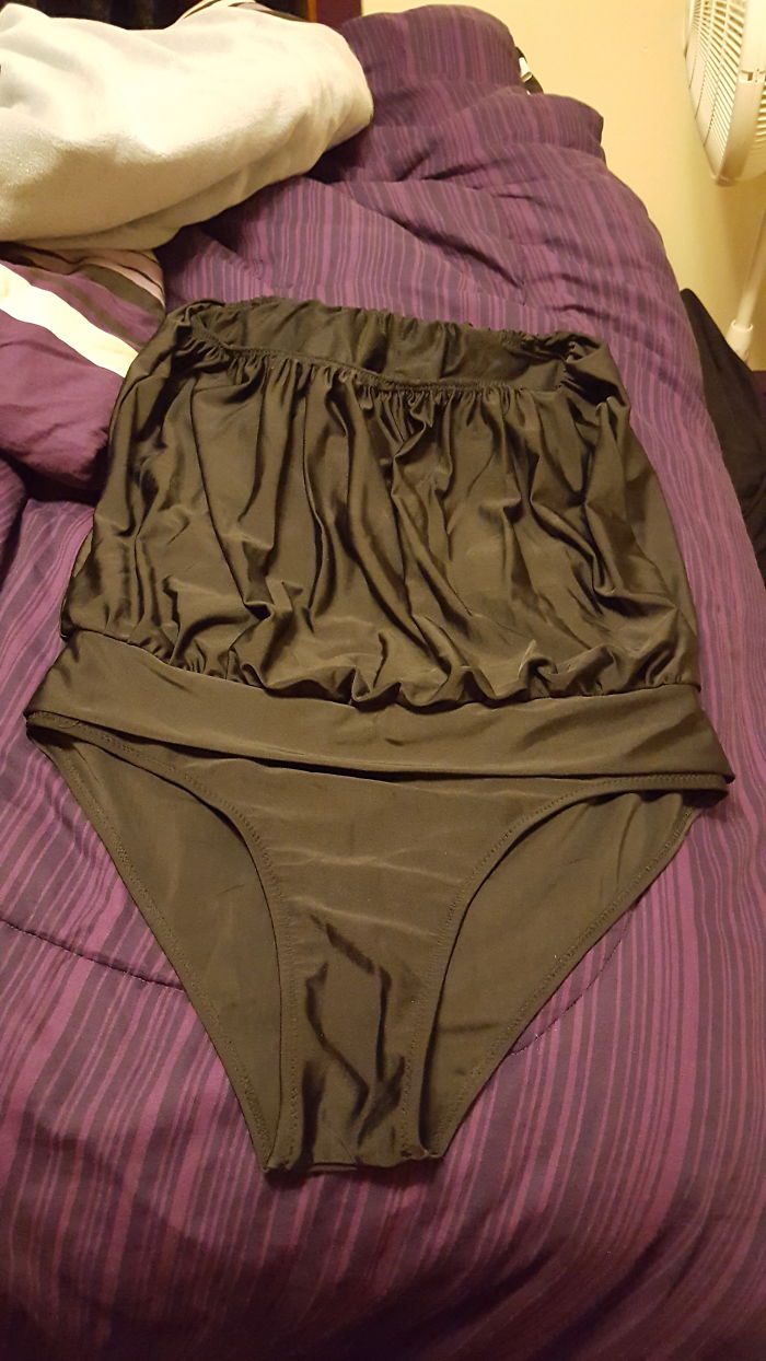 Large black swimsuit on a purple bed signifies deep regret over an online purchase.