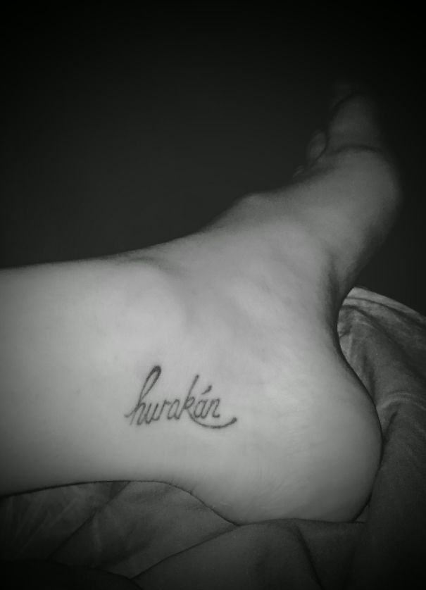 Small foot tattoo in cursive script on the inner side of the foot, showcasing minimalist design.