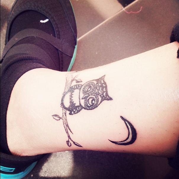 Small foot tattoo featuring a detailed owl on a branch with a crescent moon, demonstrating that less is more in design.