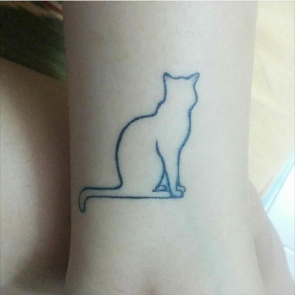 Minimalist small foot tattoo of an outlined cat, showcasing less is more design concept.