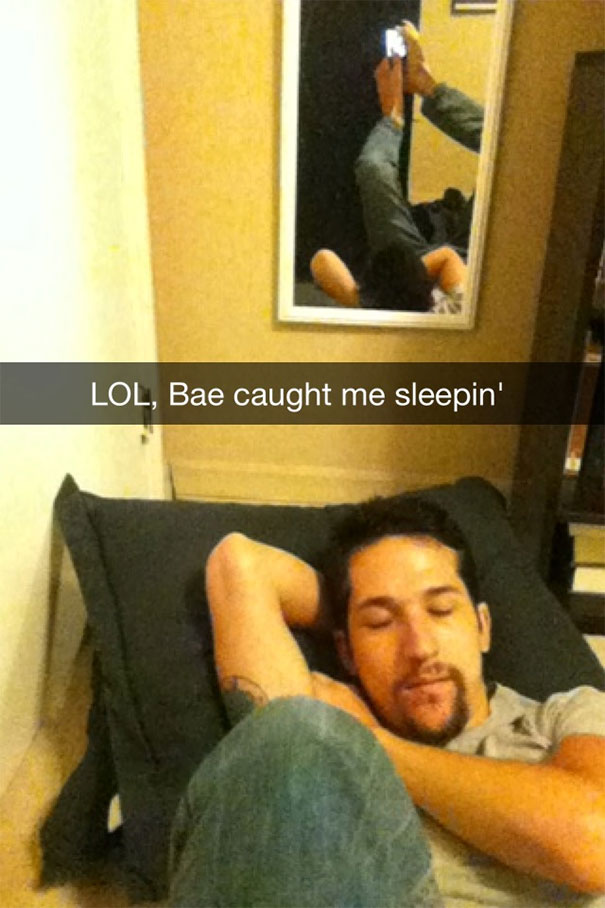 Man pretending to sleep, phone in hand, with humorous Snapchat caption visible in a mirror reflection.
