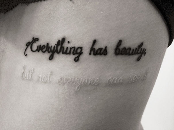 Hidden meaning tattoo with layered text: "Everything has beauty, but not everyone can see it."