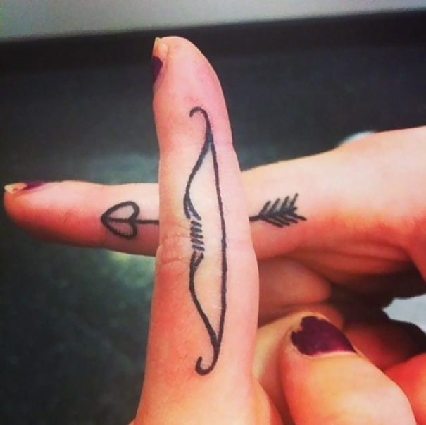 Fingers forming a hidden meaning tattoo of a bow and arrow when crossed.
