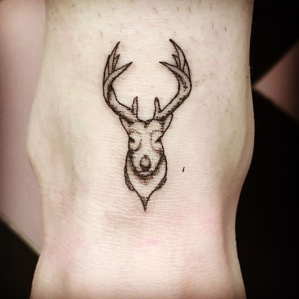 Minimalist deer head small foot tattoo design showcasing less is more concept.