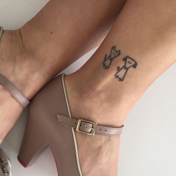Simple small foot tattoo of two outlined dogs, highlighting minimalistic tattoo design.