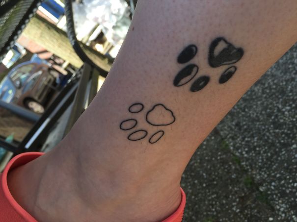 Paw print small foot tattoo with black ink and outline designs, showcasing minimalist art.